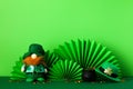 St Patricks Day paper fans, pot of gold coins, leprechaun toy, hat on green background Royalty Free Stock Photo