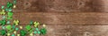 St Patricks Day shamrock and leprechaun hat corner border over a rustic wood banner background Royalty Free Stock Photo