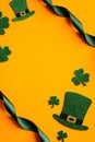 St Patricks Day vertical banner design. Top view of shamrock leaves, leprechauns hats, green ribbon on orange background. Happy