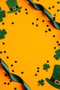 St Patricks Day vertical banner with shamrock leaves, leprechauns hats, green ribbon and confetti on orange background. Happy