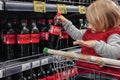 Little girl sitting in shopping cart buying coca-cola