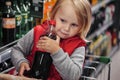 Little girl sitting in shopping cart buying coca-cola