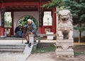 St. Petersburg, Russia - June 5, 2019, Chinese Friendship Garden, an old grandmother sits in a summer park next to a Chinese lion