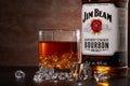 St.Petersburg, Russia - December 2019 - Bottle of Jim Beam bourbon whiskey and glass with drink and ice on brown background
