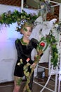 Model in an extravagant black-and-green costume of a forest nymph with a staff in the photo zone at the festival of beauty