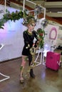 Model in an extravagant black-and-green costume of a forest nymph with a staff in the photo zone at the festival of beauty