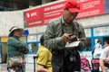 A Chinese tourist in a red baseball cap checks his ticket and passport