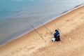 St. Petersburg, Russia - July 10, 2018: fisherman are fishing on the sandy shores of the Gulf of Finland under the bridge