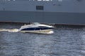 A pleasure boat sails alongside a warship on the Neva in St. Petersburg