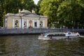 A walking boat with people swims along the river Fontanka on the background of a coffee