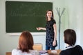 Spanish teacher, young attractive girl at the blackboard explains the learning material to