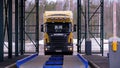 The barrier gate of the customs post is open. A Scania wagon enters the weighing control platform