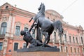 Sculpture statue Taming horse by man on Anichkov bridge on pink historical building background