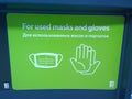 Signs on garbage container for single used masks and gloves on green background. Coronavirus hazard concept. Protect rubbish and