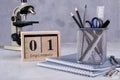 1st September. Wooden calendar, group of school supplies on a gray table.