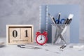 1st September. Wooden calendar, group of school supplies, red alarm clock on a gray table.