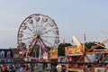 People walking around an annual fair with ferris wheel