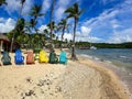 Colorful beach chairs, palm trees, sailboats tied up to the dock, and beautiful sand beach