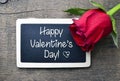 St Valentine`s Day concept.Red rose and chalkboard with text Happy Valentine`s Day on old wooden background.