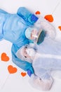 St.Valentine`s day in the hospital. Two doctors in covid 19 protective gear lying on the floor with red hearts around