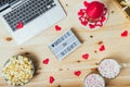 St. Valentine`s day Movie night concept. Movie night message on board, laptop, popcorn, red candle, gift, hearts decor Royalty Free Stock Photo