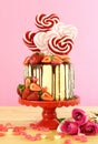 Valentine`s Day candyland drip cake decorated with heart shaped lollipops.