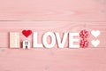 St. Valentines Day composition with word love, gift, miniature house and hearts on pink wooden background Royalty Free Stock Photo