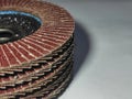 Stack of (grinding wheels) abrasive flap discs with coarse, reddish-brown sandpaper strips arranged radially around a blue central Royalty Free Stock Photo