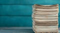 A stack of aged, off-white papers sits against a teal-colored wooden backdrop Royalty Free Stock Photo