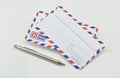 Stack of air mail envelopes with pen on white Royalty Free Stock Photo