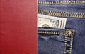 Stack of American hundred dollar bills in the back pocket of blue jeans and an international passport in the back. Royalty Free Stock Photo