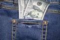 A stack of American hundred dollar bills in the back pocket of blue jeans. Money in your pocket, cash