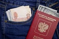 A stack of American hundred dollar bills in the international passport of Russia and Russian rubles in a pocket of blue jeans. Royalty Free Stock Photo