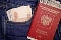 A stack of American hundred dollar bills in the international passport of Russia and Russian rubles in a pocket of blue jeans. Royalty Free Stock Photo