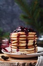 Stack of american pancakes or fritters with strawberry and blueberry jam in white plate on wooden rustic table decorated Christmas Royalty Free Stock Photo