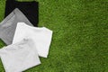 Stack of arranged different coloured mens T-shirt on grass background