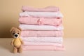 Stack of baby girl`s clothes and toy bear on white table Royalty Free Stock Photo