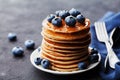 Stack of baked american pancakes or fritters with blueberries and honey syrup on rustic black table. Delicious dessert. Royalty Free Stock Photo