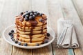 Stack of baked pancakes or fritters with chocolate sauce and frozen blueberries in a white plate