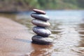 Stack of balancing pebble stones on sand and water edge as zen symbol