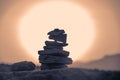 Stack of balancing stones in front of Sunset sun.