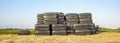 Stack of bales of hay, piled up, wrapped in black plastic, on dry grass under blue sky Royalty Free Stock Photo