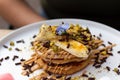 A stack of banana pancakes with slices of fresh bananas, pistachios and honey on top with chocolate slices and edible flower. Royalty Free Stock Photo