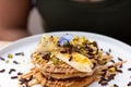 A stack of banana pancakes with slices of fresh bananas, pistachios and honey on top with chocolate slices and edible flower. Royalty Free Stock Photo