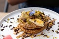 A stack of banana pancakes with slices of fresh bananas, pistachios and honey on top with chocolate slices and edible flower. Royalty Free Stock Photo