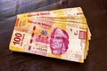 Stack of banknotes 100 Mexican pesos on a wooden table