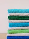 Stack of bath towels on light wooden background closeup.Pile of rainbow colored towels.Top view. Royalty Free Stock Photo