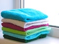 Stack of bath towels on light wooden background closeup.Pile of rainbow colored towels.Top view. Royalty Free Stock Photo