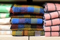 A stack of beautiful woolen blankets in red, blue, yellow, pink. A pile of soft warm blankets in store. Close up. Things for home