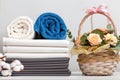 A stack of bed linen sheets bedding rolls of towels. Basket with roses flowers on the table